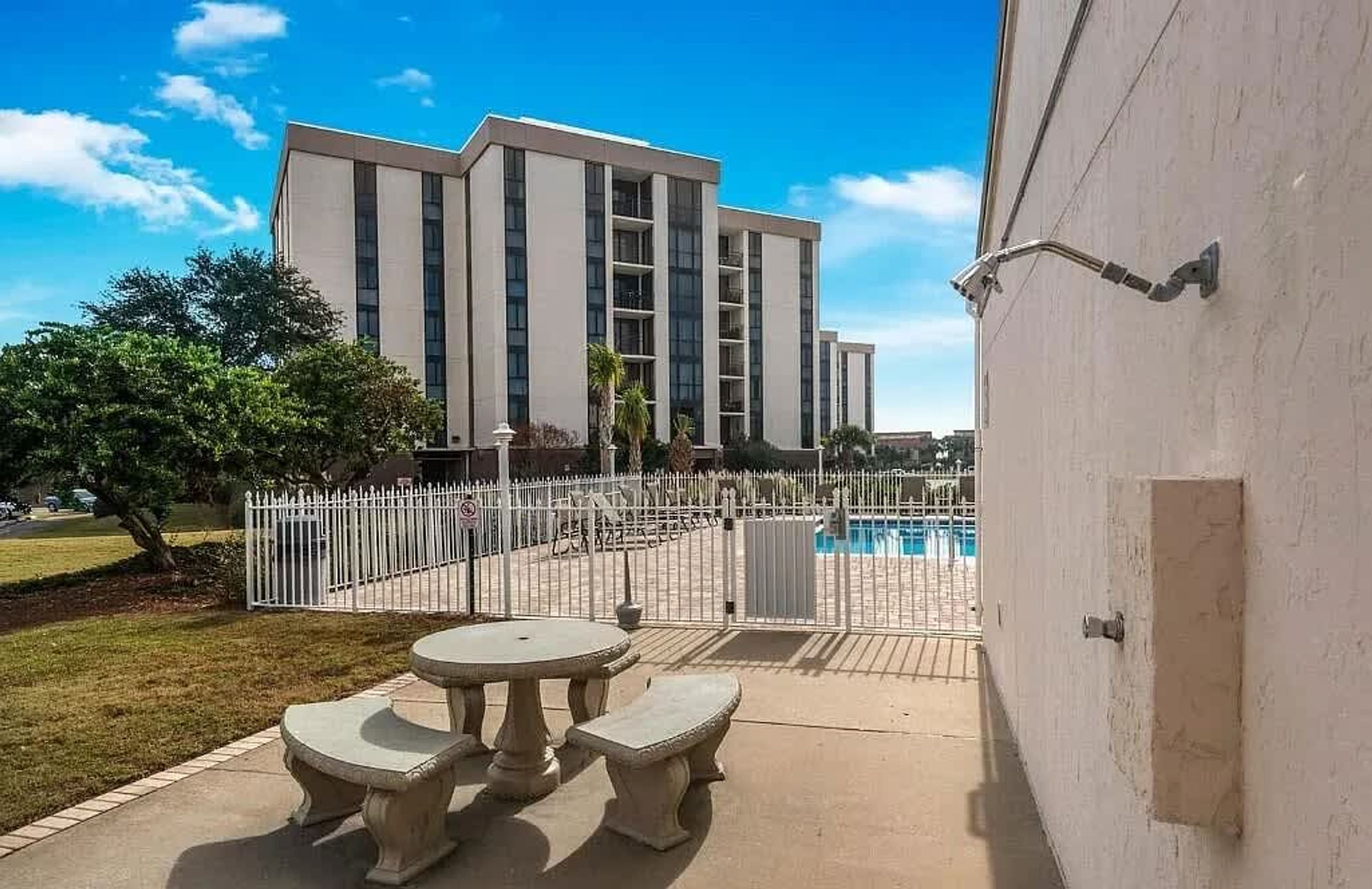 Ein Gebäude mit Schwimmbad, umzäunter Terrasse und weißem Zaun.