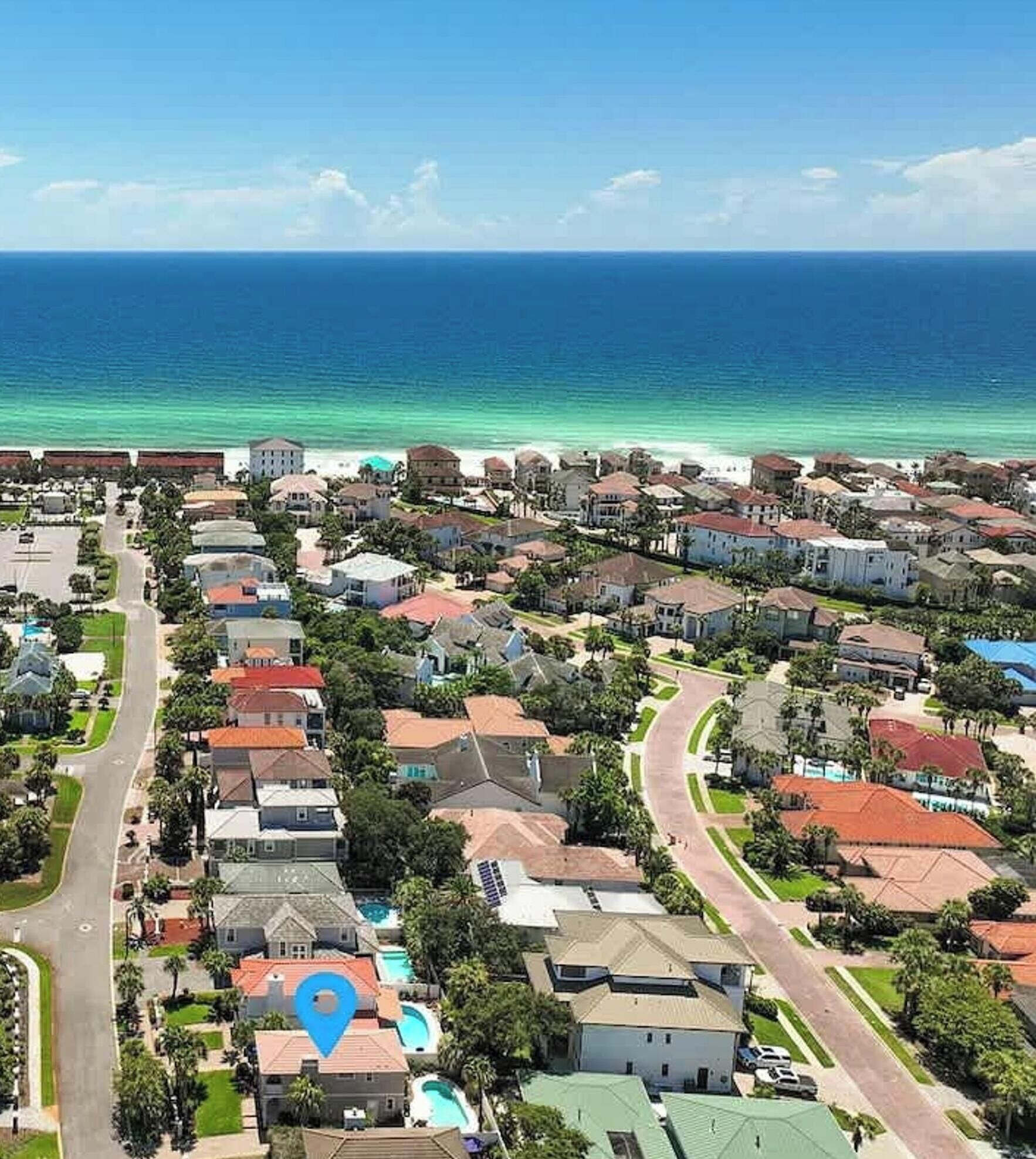 A coastal residential area with houses, a swimming pool, and a view of the ocean.
