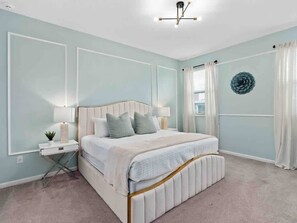 A bedroom with a bed, bedside tables, a lamp, a wall decoration, and a window with curtains. - Ultimate Group Mansion 12br Pool and Disney (Kissimmee)