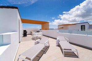 A rooftop terrace with lounge chairs, a dining area, and a pergola. - Cocotal Penthouse 3 Bedroom Golf View (Punta Cana)