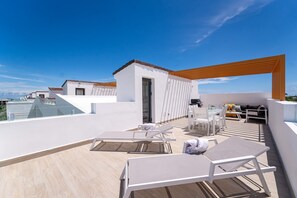 A rooftop terrace with sun loungers, a small seating area, and a wooden pergola. - Cocotal Penthouse 3 Bedroom Golf View (Punta Cana)