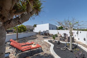 Eine Dachterrasse mit Liegestühlen, einem kleinen Tisch und einem weißen Gebäude im Hintergrund.