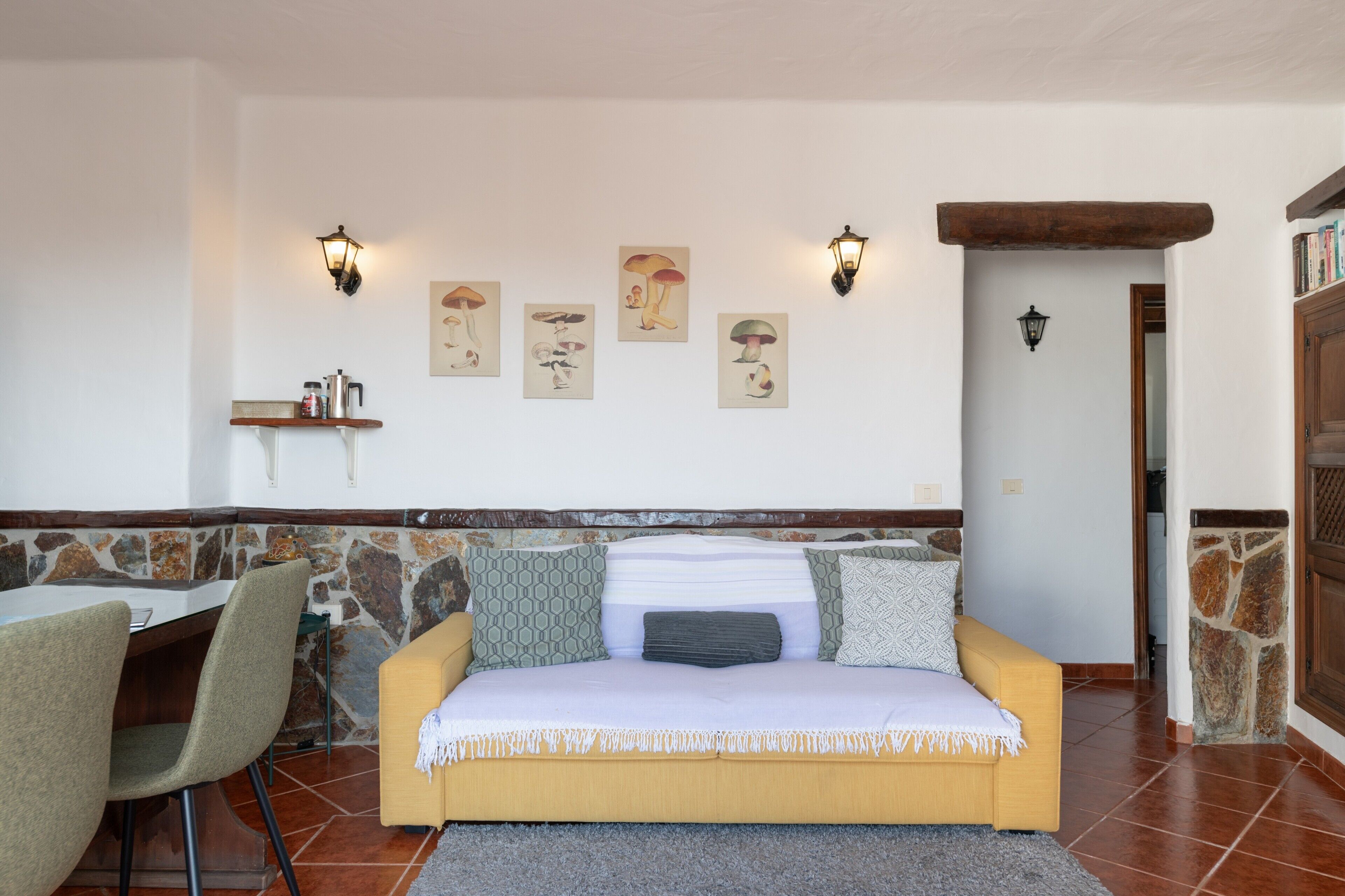 Ein gemütlicher Wohnbereich mit einer Couch, Sesseln, einer Steinwand und Kunstwerken an der Wand.