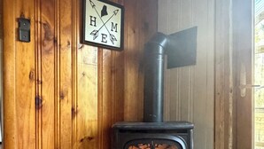 A wooden interior with a wood-burning stove, a door with a window, and a sign on the wall.