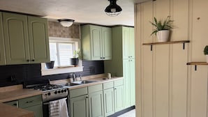 A kitchen with green cabinets, a stove, and a sink.