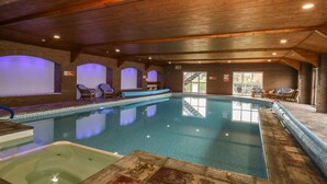 Piscina interior con sillones de descanso y un jacuzzi.