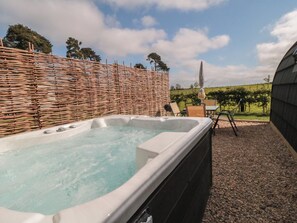 A hot tub with a wicker fence, outdoor seating, and a vineyard in the background. - Starlight Sanctuary (Malton)