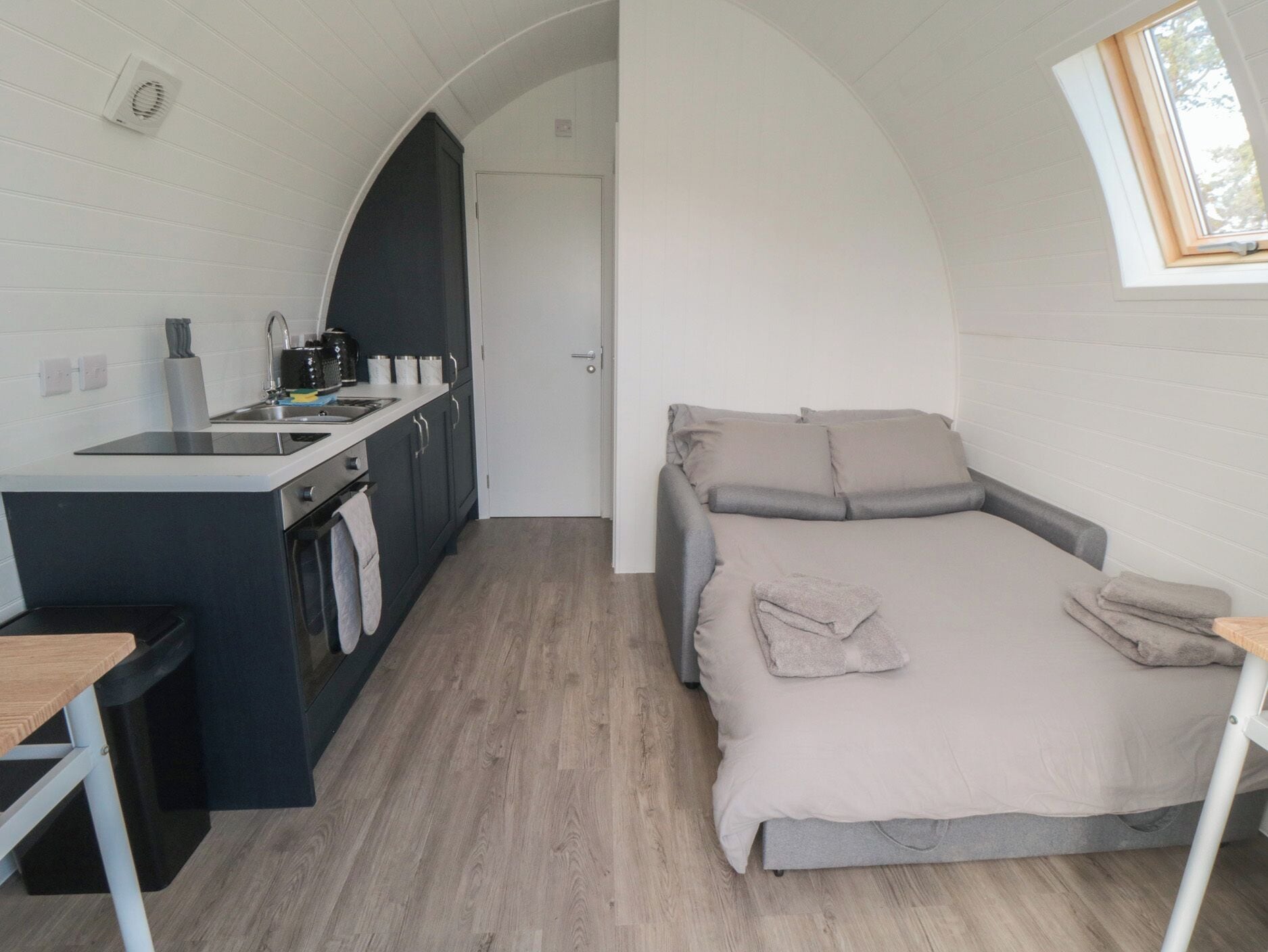 Ein gemütlicher Raum mit Küchenzeile, einem Bett mit Kissen und einem Oberlicht.
