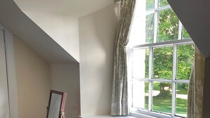Ein Zimmer mit Fenster, Heizkörper, Kommode und Spiegel.