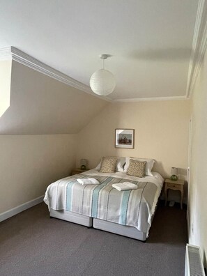 A bedroom with a bed, two bedside tables, a hanging light fixture, and a framed picture on the wall.