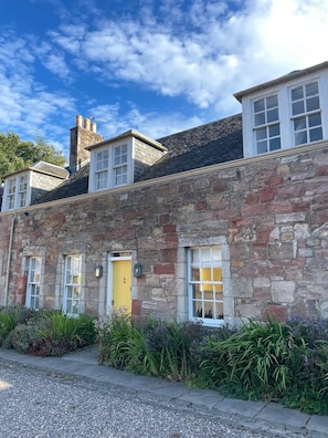 A stone building with multiple windows, a yellow door, and a gravel driveway. - No 1 Stable Yard, Wemyss Castle Estate (Kirkcaldy)
