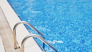 A swimming pool with clear blue water, metal handrails, and a tiled deck. - Tulivu By Edmor Suites (Nairobi)