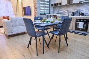 Una sala moderna con una mesa de comedor, sillas, un sofá y una zona de cocina con electrodomésticos.