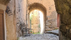 An arched stone doorway leading to a courtyard with a table and chairs. - Authentic stone house in the heart of a medieval village · sea 20 min away (Lama)
