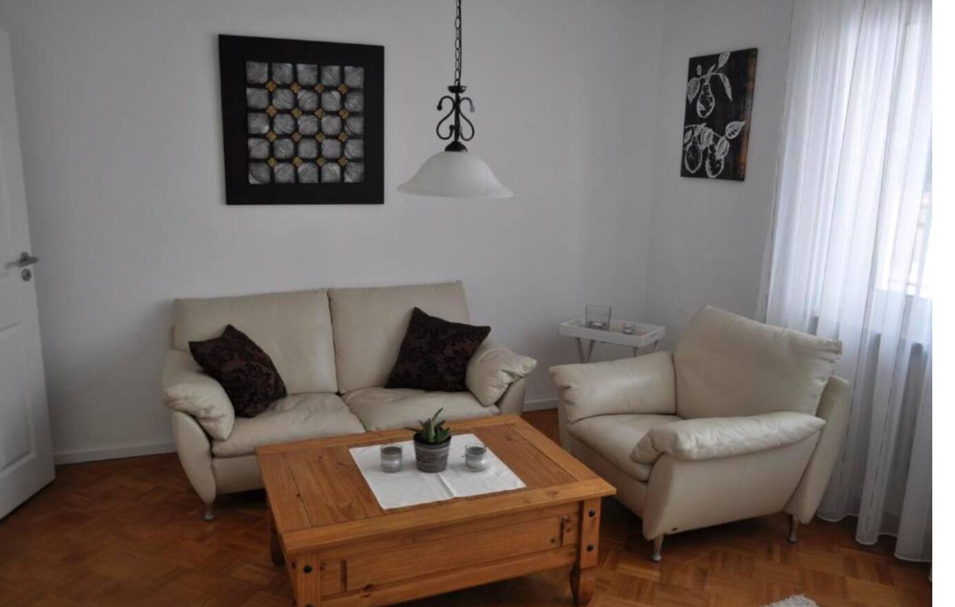 Ein Wohnzimmer mit zwei Sofas, einem Holztisch und einer Pendelleuchte.