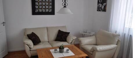 Ein Wohnzimmer mit zwei Sofas, einem Holztisch und einer Pendelleuchte.