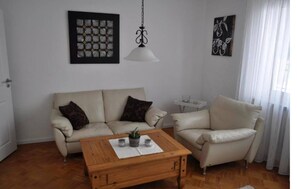 Ein Wohnzimmer mit zwei Sofas, einem Holztisch und einer Pendelleuchte.
