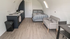 Habitación compacta con kitchenette, cama, sofá y una mesa.
