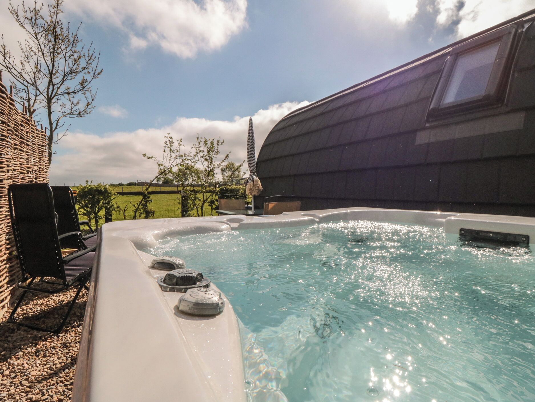 A hot tub with a brick wall and a tree in the background.