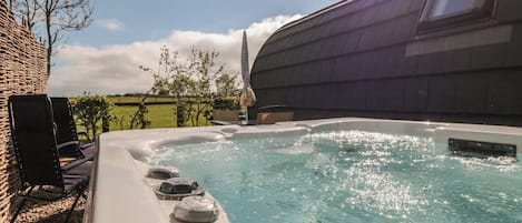 A hot tub with a brick wall and a tree in the background.