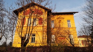 A yellow building with multiple windows and a balcony, surrounded by trees. - Vila Veselova (Ljubljana)