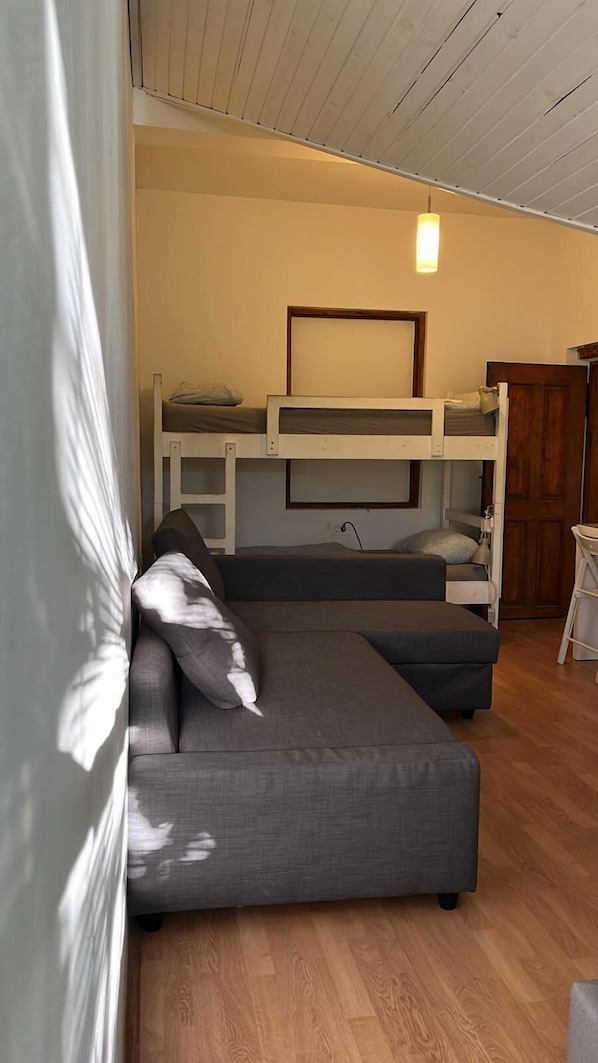 A room with a sofa, bunk beds, a wooden ceiling, and a hanging light fixture. - Vila Veselova (Ljubljana)