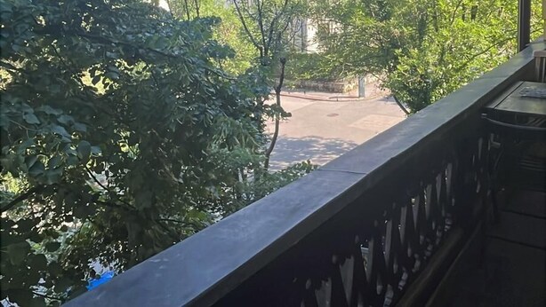 A balcony with a view of a building with a red roof and a clear blue sky. - Vila Veselova (Ljubljana)