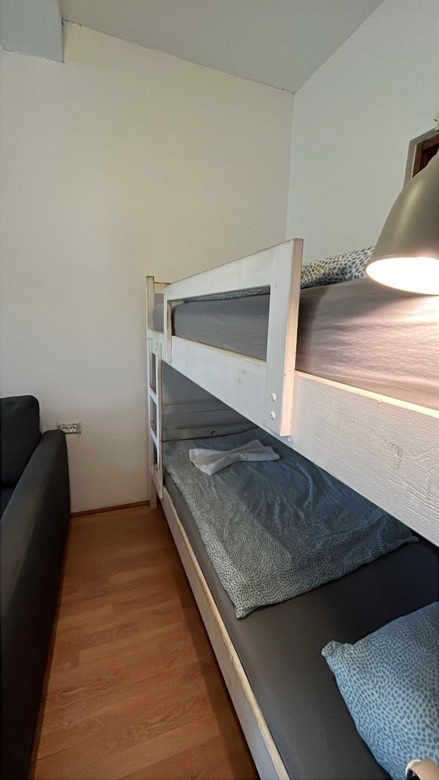 En køjeseng med sengegavl, et natbord og en lampe.