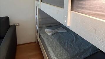 En køjeseng med sengegavl, et natbord og en lampe.