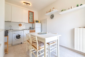 A compact kitchen with a washing machine, a microwave, and a dining area with a table and chairs.