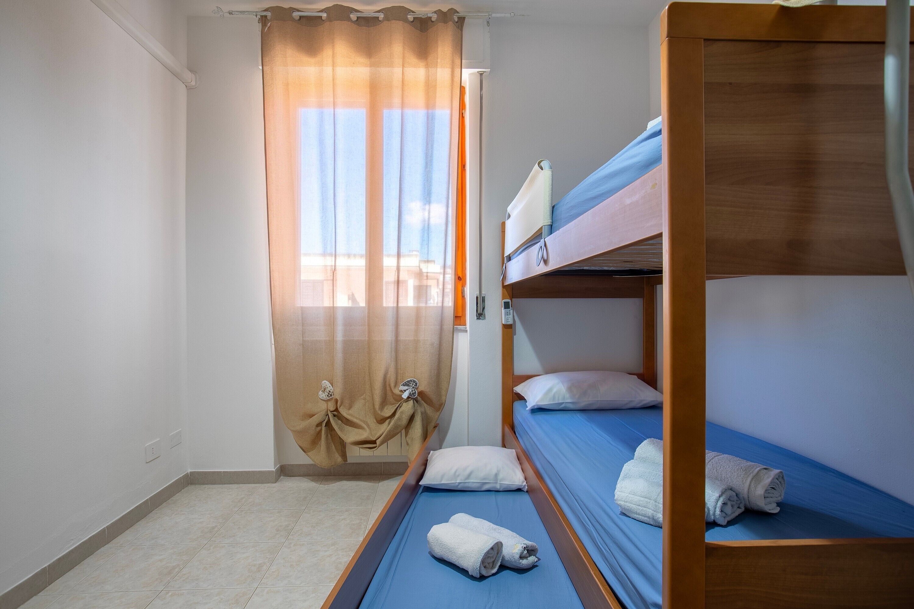 Ein Zimmer mit einem Etagenbett, einem Vorhang und einem Fenster.