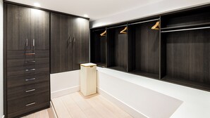 Ein moderner Kleiderschrank mit dunklen Holzschränken, einer weißen Bank und Holzaufhängern.