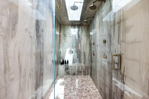A modern bathroom with a glass shower enclosure, marble walls, and a tiled floor. - Saint Ives Reserve - Sunset Strip Retreat w/ Epic City-to-Ocean Views (Los Angeles)