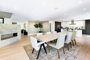 A modern kitchen with a central island, built-in appliances, and a dining area with a marble table and chairs. - Saint Ives Reserve - Sunset Strip Retreat w/ Epic City-to-Ocean Views (Los Angeles)