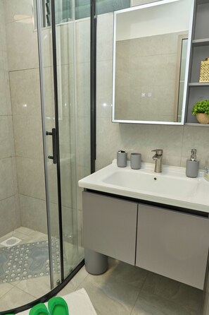 Apartamento, vista para a cidade | Banheiro | Chuveiro, produtos de toalete grátis, chinelos, toalhas de banho