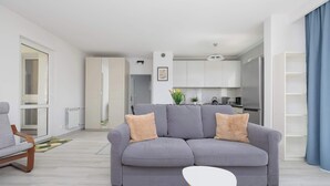 Una sala de estar moderna con un sofá gris, una mesa de centro blanca y una silla de madera.