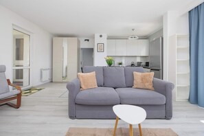 Una sala de estar moderna con un sofá gris, una mesa de centro blanca y una silla de madera.