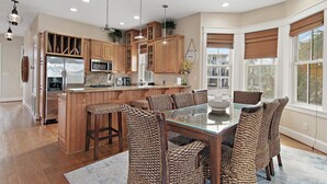 Una cocina moderna con armarios de madera, electrodomésticos de acero inoxidable y una mesa de comedor de vidrio con sillas de mimbre.