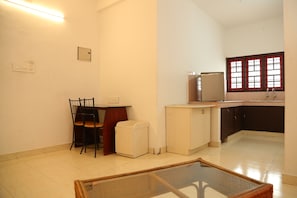 A compact kitchen with a refrigerator, a sink, and a window with red frames.