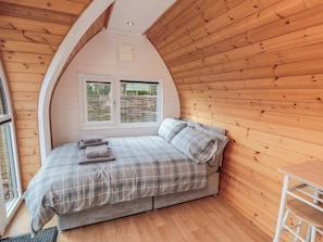 Un dormitorio con una cama, una ventana y techo de madera.