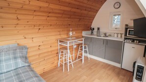 Una cocina compacta con microondas, fregadero y un reloj en la pared.