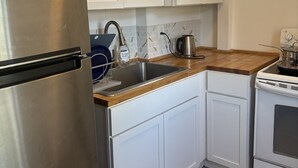 Una cocina con armarios blancos, un refrigerador de acero inoxidable, un fregadero y una estufa.