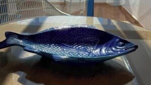Una escultura de pez sobre una mesa en una habitación con vistas amplias a través de grandes ventanales.