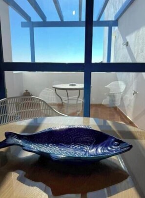 Eine Fischskulptur steht auf einem Tisch in einem Raum mit Blick durch große Fenster.