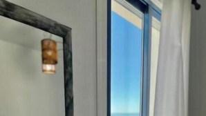 Un dormitorio con una cama, una ventana con vistas y un espejo en la pared.