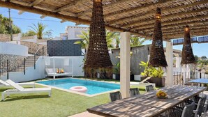 A pool area with a thatched roof, lounge chairs, and a dining table. - Elegant Villa in Moraira for 6 · Private Pool Close to Town – ALMARE (Teulada)