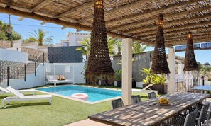 A pool area with a thatched roof, lounge chairs, and a dining table. - Elegant Villa in Moraira for 6 · Private Pool Close to Town – ALMARE (Teulada)