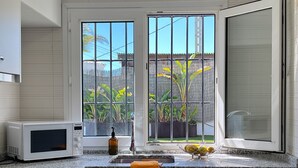 A kitchen with a microwave, sink, and window with a view of greenery. - Elegant Villa in Moraira for 6 · Private Pool Close to Town – ALMARE (Teulada)