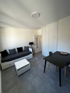 Ein modernes Wohnzimmer mit einer Couch, einem Couchtisch, einem Esstisch und einer Lampe.