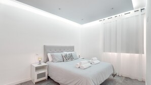 Ein modernes Schlafzimmer mit Bett, Nachttisch und Vorhängen.
